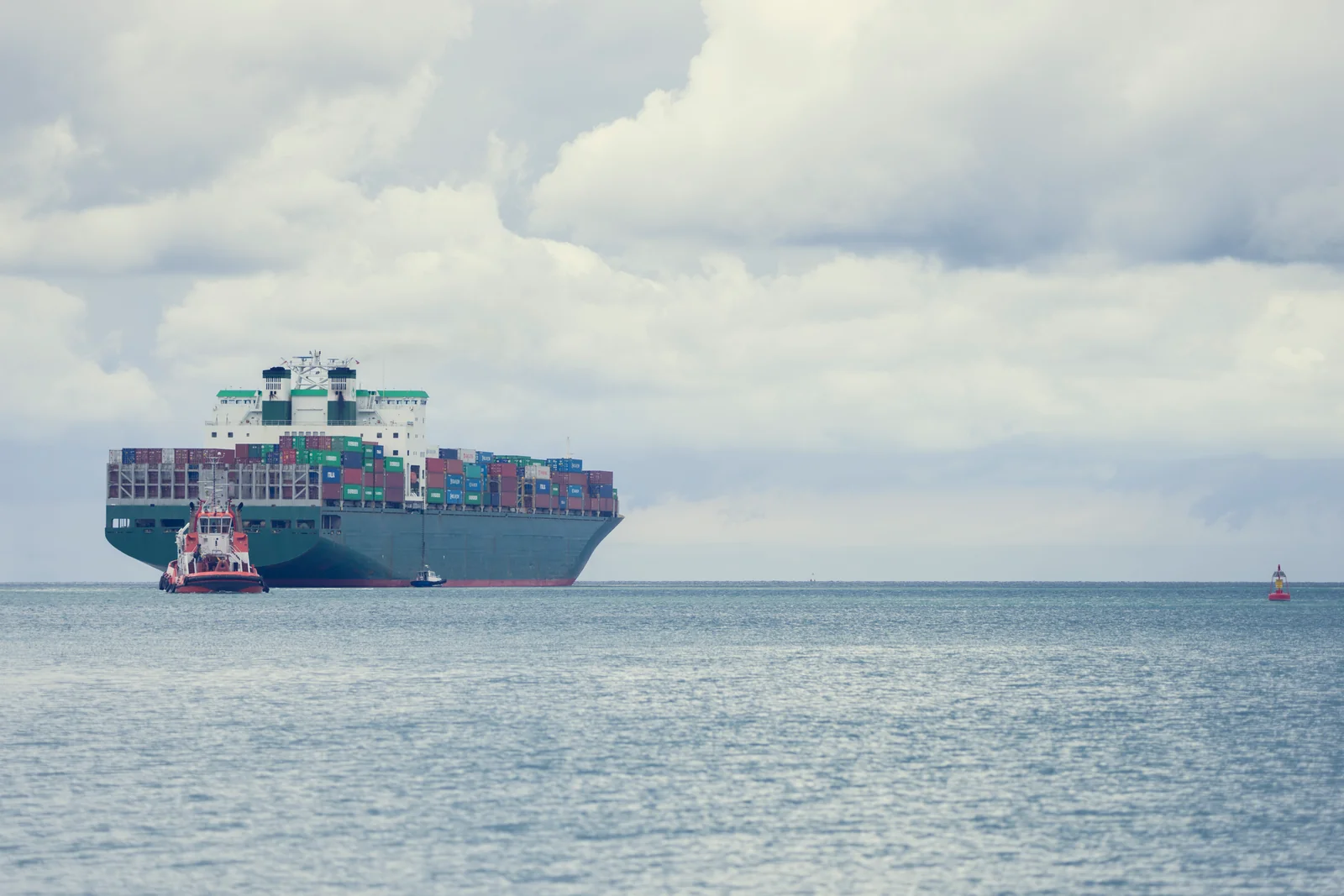 A cargo vessel approaching a port on calm blue water